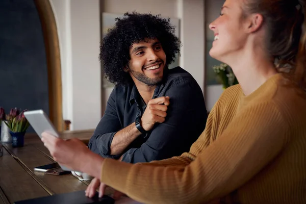 Alegre hombre y mujer riendo y hablando en la cafetería usando tableta digital — Foto de Stock
