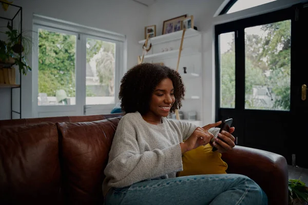 Glückliche Frau entspannt sich auf bequemer Couch und surft mit dem Smartphone in sozialen Medien — Stockfoto