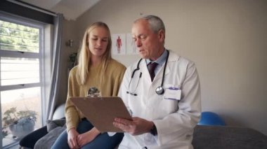 Üst düzey bir erkek fizyoterapistin klinikteki muayene odasında oturan kadın bir hastaya tavsiyede bulunması.