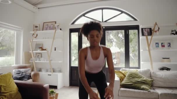Уставшая молодая африканка, стоящая в гостиной и занимающаяся спортом — стоковое видео