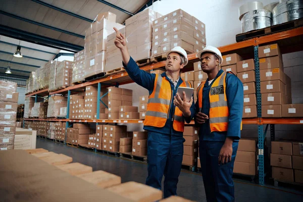 Ingegneri di fabbrica esaminando le loro scorte presso il magazzino di produzione con tablet digitale — Foto Stock