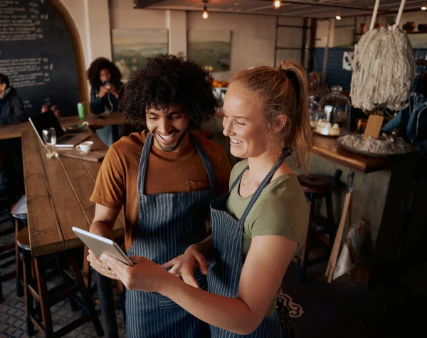 Vista de ángulo alto de los propietarios de cafés jóvenes de pie usando tableta digital usando delantal — Foto de Stock