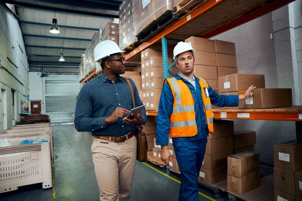 Lavoratori multirazziali discutono di magazzino indossando caschi di sicurezza — Foto Stock