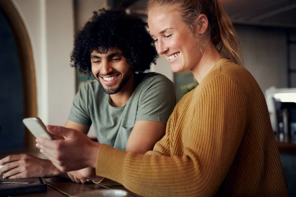 Mooie vrouw en knappe man kijken video in smartphone en lachen in cafe — Stockfoto