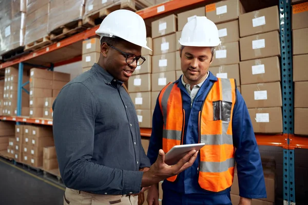 Ingenieros de fábrica multiétnicos comprobando tableta digital en almacén de fábrica — Foto de Stock