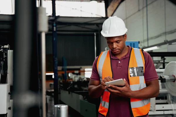 Giovane operaio industriale afroamericano che lavora su tablet digitale in fabbrica - tu maschio nero che controlli macchinari moderni — Foto Stock