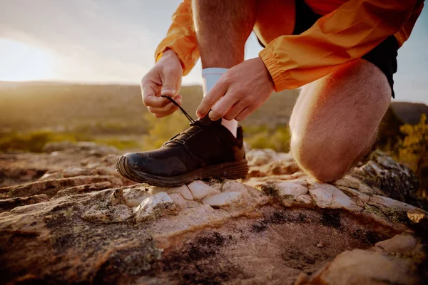 Close-up van de handen van fitte mannelijke jogger veters strikken voorbereiding voor cross country bergpad lopen in de natuur bij zonsopgang — Stockfoto
