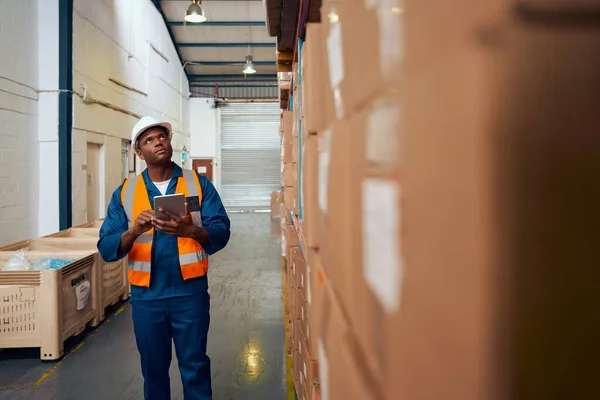 Afro-Amerikaanse fabrieksarbeider controleren voorraad inventaris met behulp van digitale tablet in modern magazijn — Stockfoto