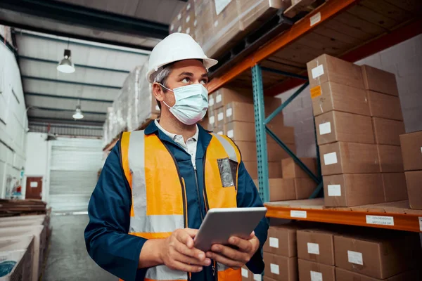 Retrato de un trabajador masculino que trabaja en el almacén con una tableta digital con máscara de seguridad en el almacén - coronavirus — Foto de Stock