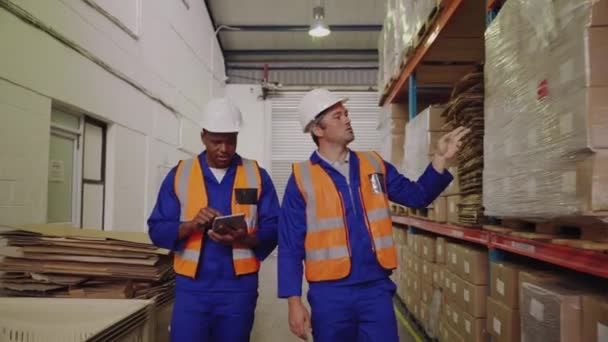 Dijital tablet kullanan erkek işçi amiriyle yürüyor ve depodaki envanteri kontrol ediyor. — Stok video