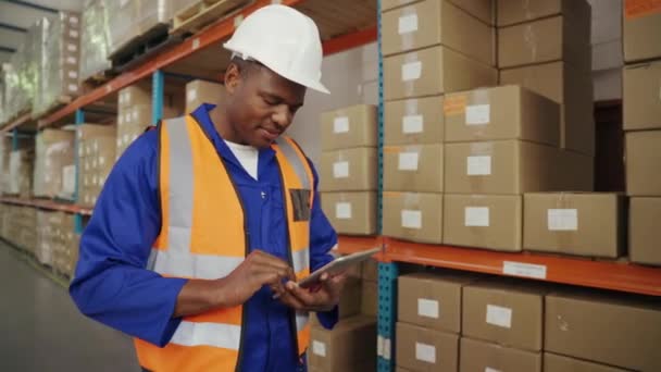 Trabajador africano que comprueba el inventario en el almacén de una empresa de fabricación en la tableta de pantalla táctil — Vídeos de Stock