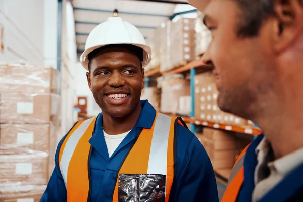 Happy african male staff looking at his coworker in industrial plant