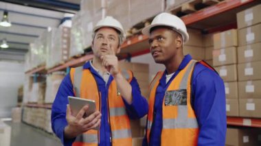 Depoda dijital tablet kullanan çok ırklı erkek işçilerin güvenlik kameraları var.
