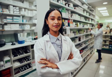 Çapraz elleri olan genç bir eczacı ve kimyager. Arka planda çalışan bir meslektaşı var.