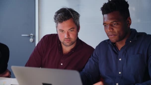 Бизнесмены смешанной расы рассматривают ноутбук, работающий над проектом сотрудничества в офисе — стоковое видео