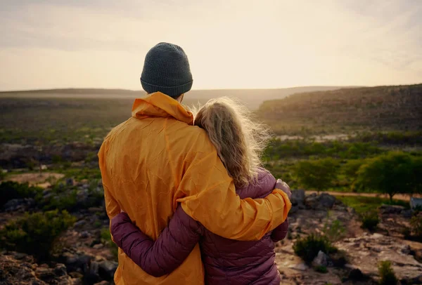 Vista trasera de un hombre joven y una mujer abrazándose mientras mira el hermoso amanecer — Foto de Stock