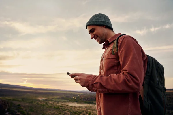 Щасливий чоловічий пішохід, використовуючи смартфон на вершині гори — стокове фото