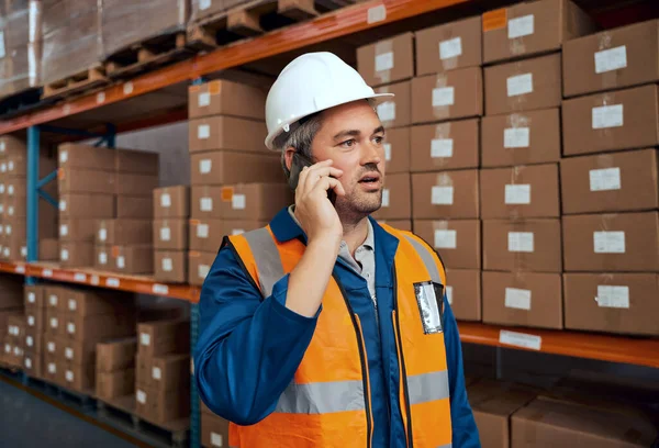 Férfi technikus beszél okostelefonon visel keménykalapot a gyártó raktárban — Stock Fotó