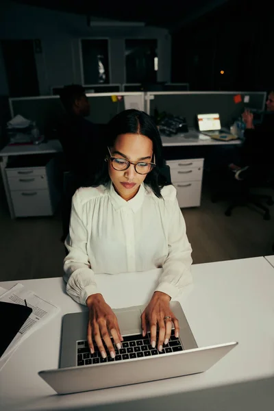 Retrato de uma jovem executiva vestindo óculos digitando em laptop portátil no local de trabalho — Fotografia de Stock