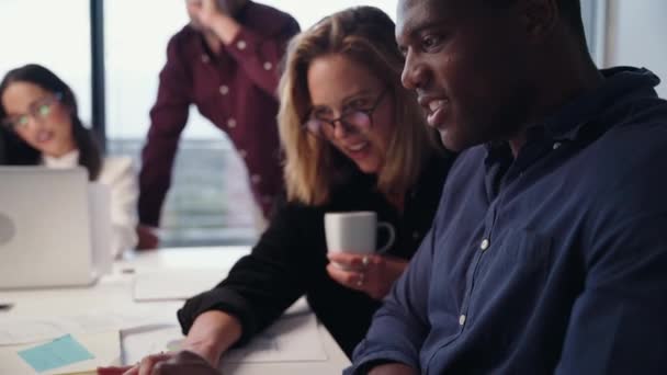 Mujer de negocios caucásica y colega masculino de raza mixta trabajando juntos ayudándose mutuamente con la presentación escribiendo en el portátil — Vídeo de stock