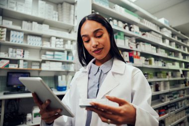 Kimyagerde çalışan Afrikalı kadın eczacı dijital tabletteki ilaç detaylarını kontrol ediyor.