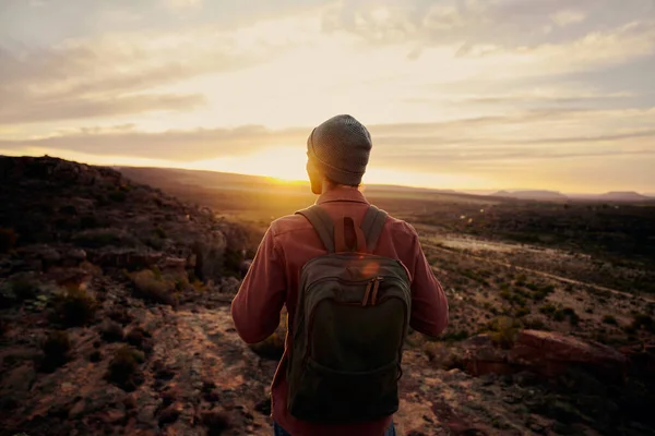 Achteraanzicht van jonge mannelijke wandelaar die op de rand van de klif staat en geniet van zonsopgang kijkend naar de vallei en de bergen — Stockfoto