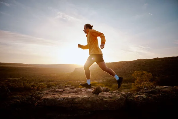 Ajuste joven atleta hombre corriendo por una colina durante el amanecer —  Fotos de Stock