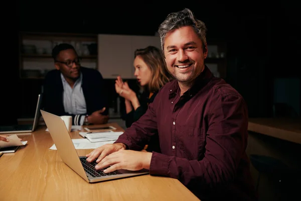 Portret van een succesvolle mannelijke bedrijfsleider met laptop met zijn team op de achtergrond in het kantoor — Stockfoto