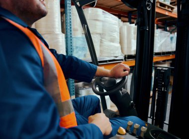 Forklift kullanan bir depo çalışanının yakın çekimi.