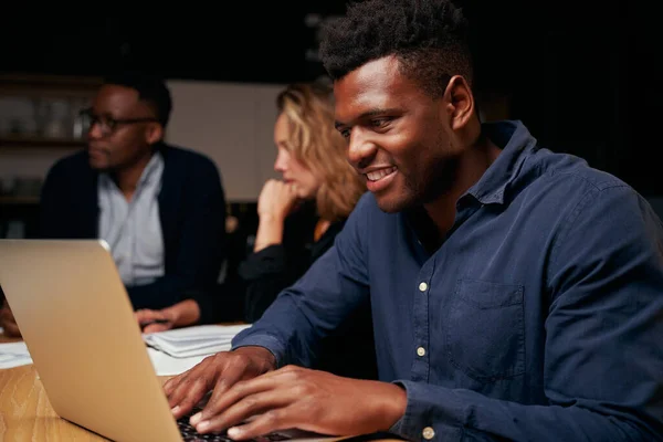 Retrato lateral de um jovem empresário africano sorridente usando laptop no local de trabalho no escritório — Fotografia de Stock