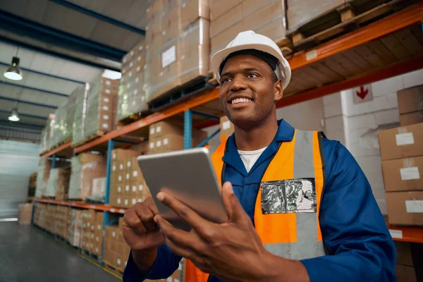 Trabalhador da fábrica sorrindo inspecionando os produtos de fabricação usando tablet digital no armazém — Fotografia de Stock