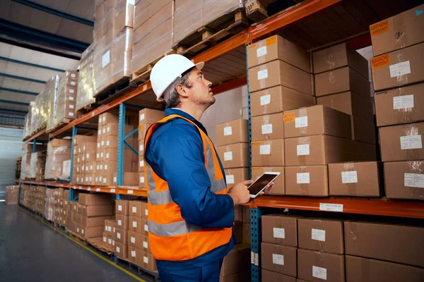 Técnico masculino en trabajo de seguridad llevando registros de stock en tableta digital — Foto de Stock