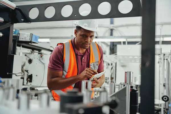 Técnico industrial usando chapéu duro examinando estoque na indústria usando tablet digital — Fotografia de Stock