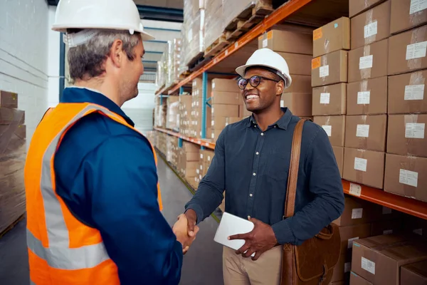 Operaio africano stringere la mano con il suo partner indossa casco di sicurezza tenendo tablet in mano — Foto Stock