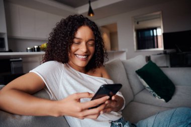 Hücresel cihazda arkadaşlarına mesaj atarken gülümseyen melez bir kadın. 