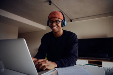 Evde dizüstü bilgisayar kullanarak çalışan Afro-Amerikan erkek. Sanal görüşme için kulaklıkla evde çalışan mutlu Afrikalı Amerikalı erkek. Yüksek kalite fotoğraf 