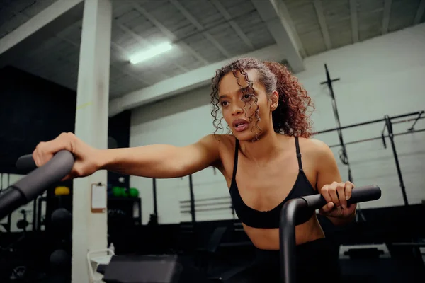 Mulher afro-americana usando um treinador elíptico durante o treinamento cross fit. Uma atleta a exercitar-se no ginásio. Foto de alta qualidade — Fotografia de Stock