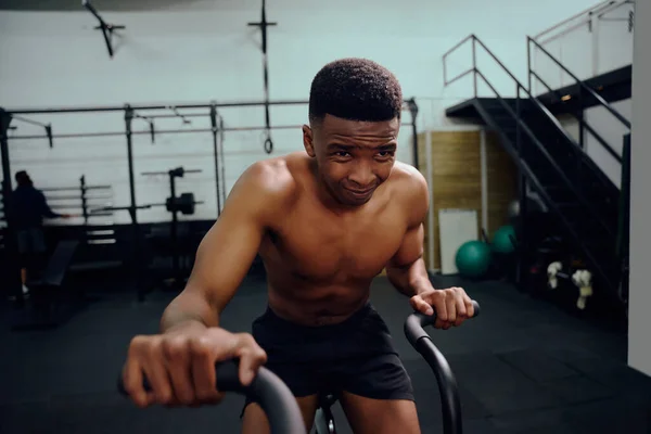 Afroameričan používající eliptický trenér během tréninku cross fit. Muž sportovec intenzivně cvičí v tělocvičně. Kvalitní fotografie — Stock fotografie