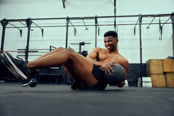 Homem afro-americano fazendo um treino intenso no ginásio. Atleta masculino a fazer abdominais com bola de remédios. Foto de alta qualidade — Fotografia de Stock