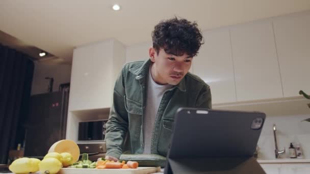 Ung blandras hane matlagning middag hemma söka recept på laptop — Stockvideo