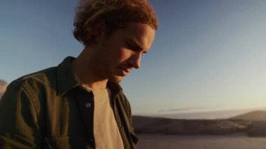 Genç beyaz bir erkek sahilde telefonda mesajlaşıyordu. Telefona bakan adama yaklaş. Yüksek kalite 4k görüntü 