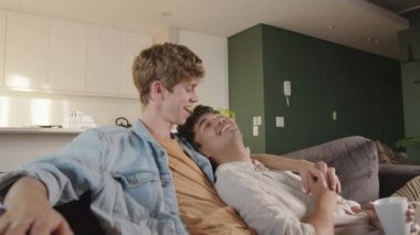 Sevimli melez erkek eşcinsel çift kanepede film izlerken birlikte vakit geçiriyorlar.