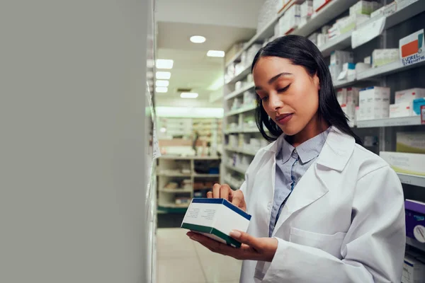 Žena zkontroluje krabičku s léky, přečte si datum spotřeby a instrukce stojící v uličce chemika — Stock fotografie