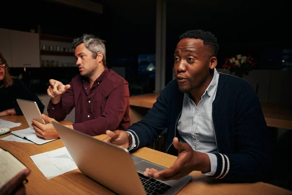 Dois empresários diversos usando laptop e tablet digital discutindo o trabalho no escritório — Fotografia de Stock