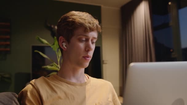 Homem caucasiano trabalhando em laptop conversando com clientes em chamada de vídeo com fones de ouvido — Vídeo de Stock