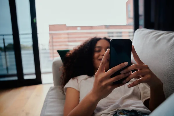 Gemengd ras vrouwelijke tiener met afro sms 'en vrienden op cellulaire apparaat terwijl glimlachen — Stockfoto