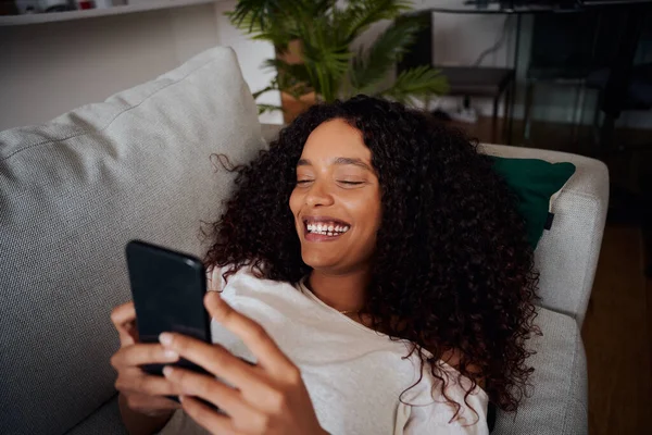Misto raça fêmea adolescente sorrindo enquanto mensagens namorado no dispositivo celular — Fotografia de Stock