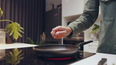 Genç beyaz erkek evde yemek pişiriyor sıcak tencerede sebze kızartıyor. 