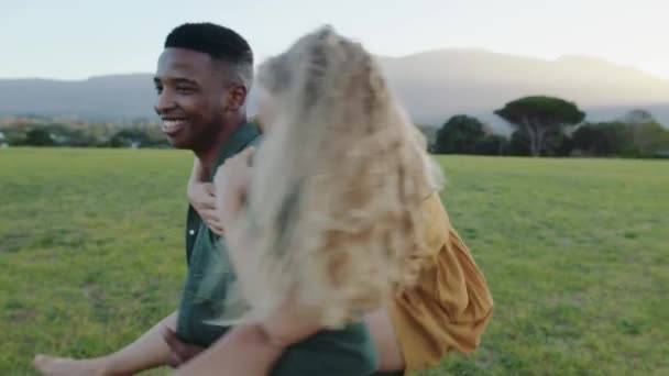 Pareja romántica de carrera mixta disfrutando del tiempo juntos vinculándose mientras da paseos en paquete de cerdito en el parque — Vídeo de stock