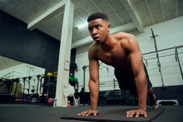 Junge afroamerikanische Männer machen Liegestütze im Fitnessstudio. Gemischtes Rennen, männlicher Personal Trainer, der drinnen Crossfit macht. Hochwertiges Foto — Stockfoto